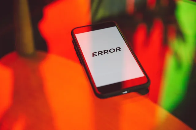 A smartphone displaying an 'ERROR' message surrounded by vibrant red and green reflections indoors. Deciding when to fix the app before buying more traffic