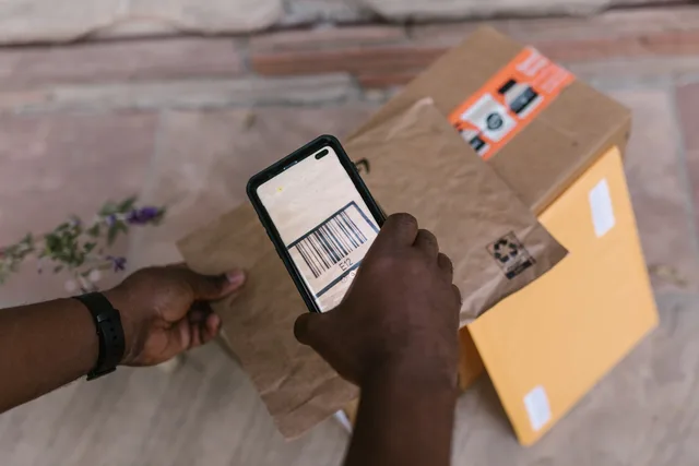 A person scans package barcodes using a smartphone for delivery logistics. Matching an install ad with the real app experience